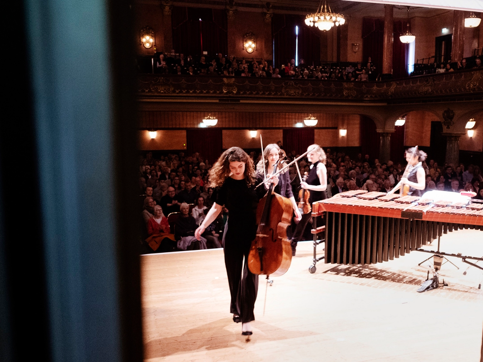 Impression vom Heidelberger Frühling – Foto aus dem Backstagebereich auf die Bühne. Vier Musiker*innen verlassen mit ihren Instrumente gerade die Bühne.
