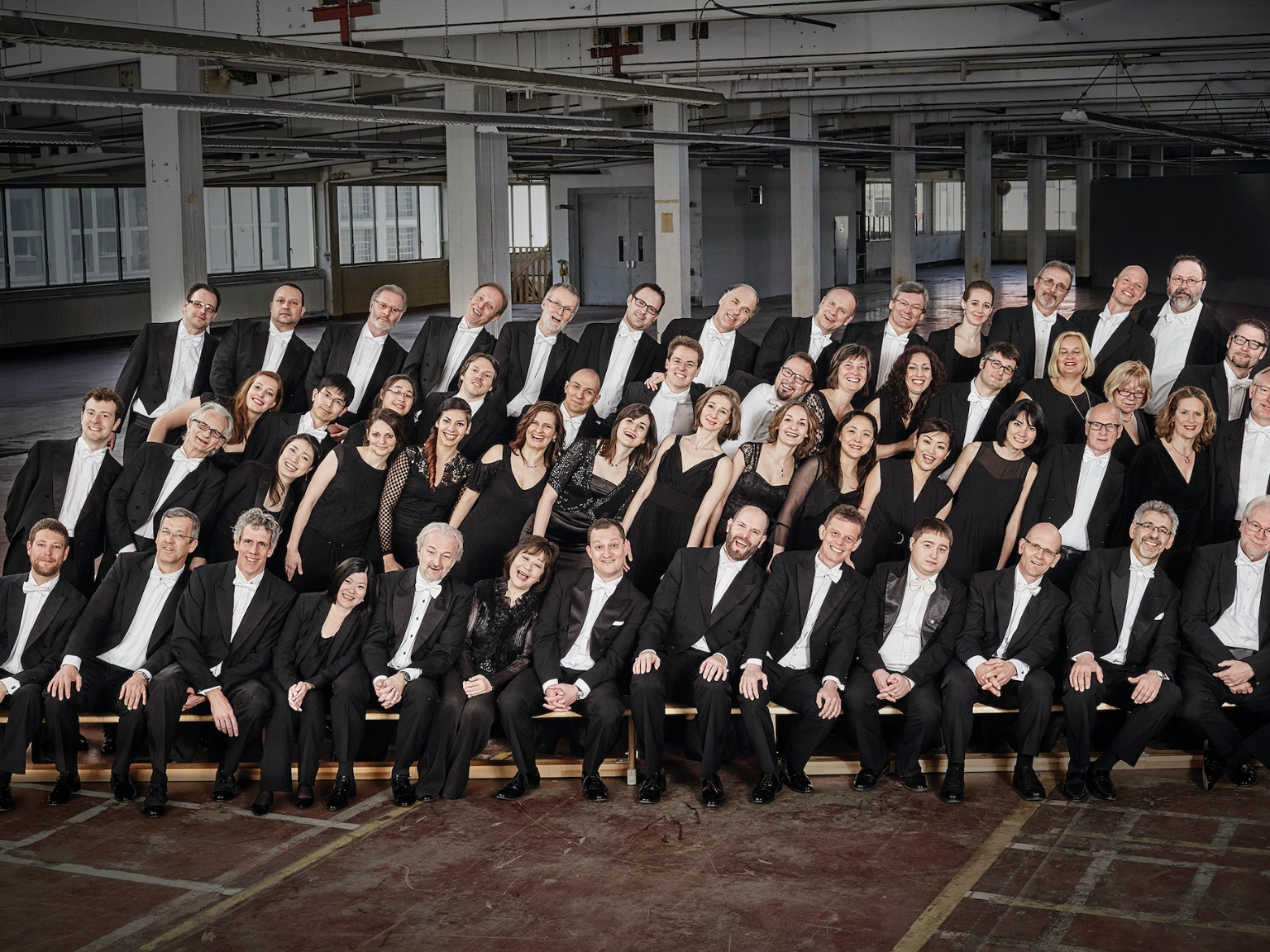 Orchesterbild der Nürnberger Symphoniker. Alle Musiker*innen neigen sich auf dem Gruppenbild nach rechts.
